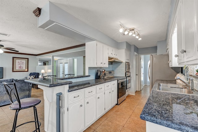 kitchen with a sink, open floor plan, stainless steel appliances, a peninsula, and white cabinets