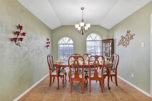 tiled dining space featuring an inviting chandelier, baseboards, and vaulted ceiling