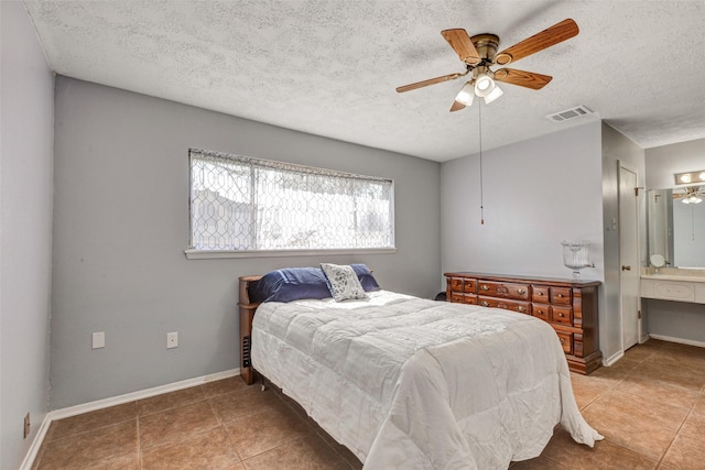 tiled bedroom with visible vents, a textured ceiling, baseboards, and a ceiling fan