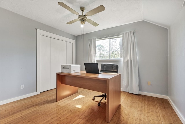 unfurnished office with light wood-type flooring, baseboards, a textured ceiling, and vaulted ceiling