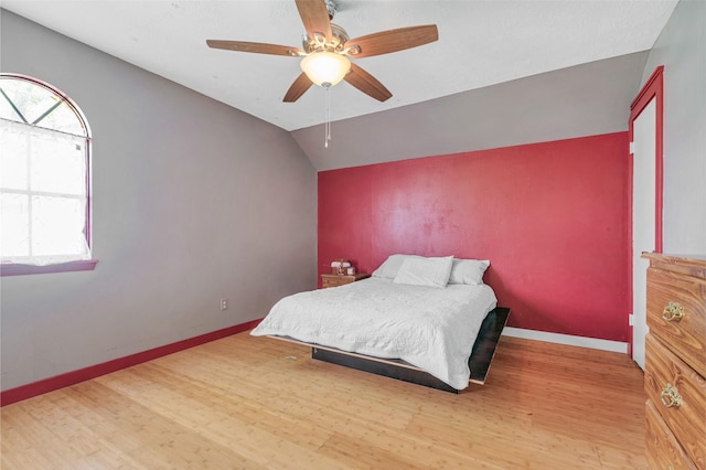 bedroom with multiple windows, wood finished floors, and vaulted ceiling