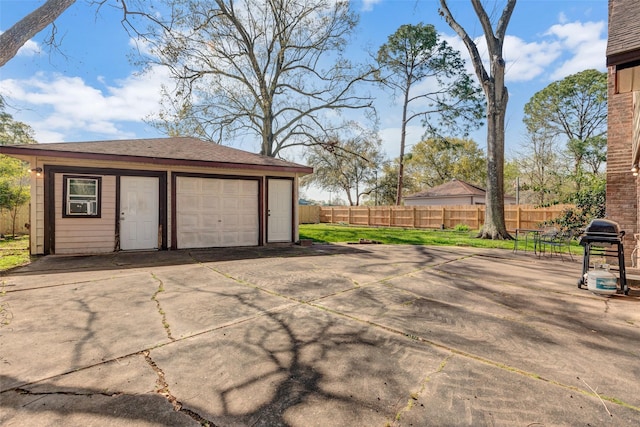 garage with concrete driveway and fence