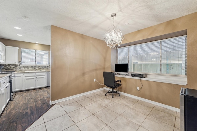 office area featuring light tile patterned floors, baseboards, and a textured ceiling