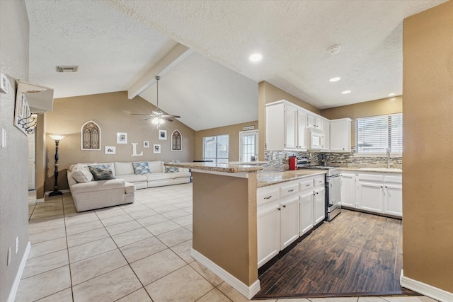 kitchen with stainless steel range, visible vents, white microwave, open floor plan, and white cabinetry