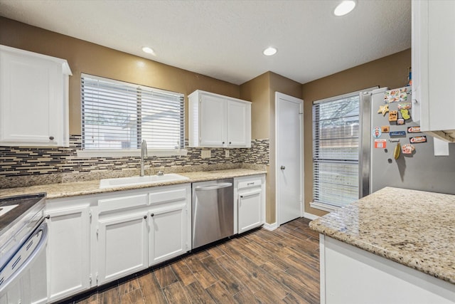 kitchen with dark wood-style floors, tasteful backsplash, appliances with stainless steel finishes, white cabinetry, and a sink