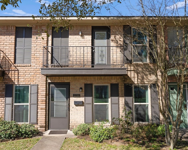 view of property with brick siding and a balcony