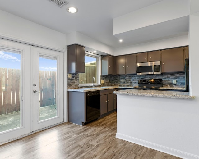 kitchen with dark brown cabinetry, visible vents, decorative backsplash, wood finished floors, and black appliances