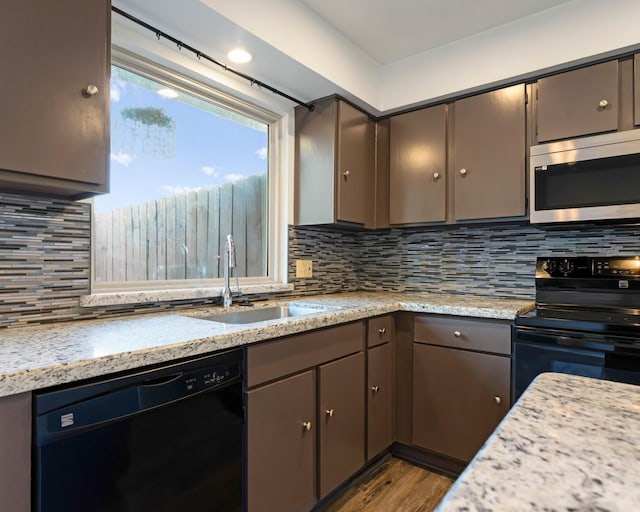 kitchen with dark wood-style floors, tasteful backsplash, gray cabinetry, a sink, and black appliances