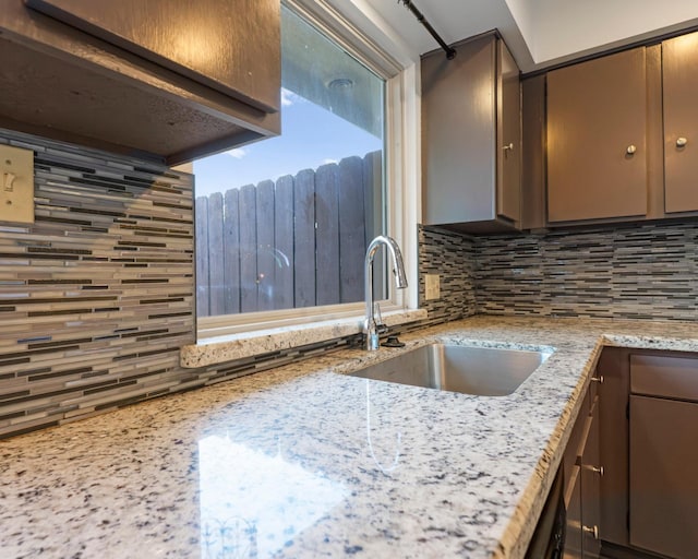 kitchen featuring light stone counters, backsplash, and a sink