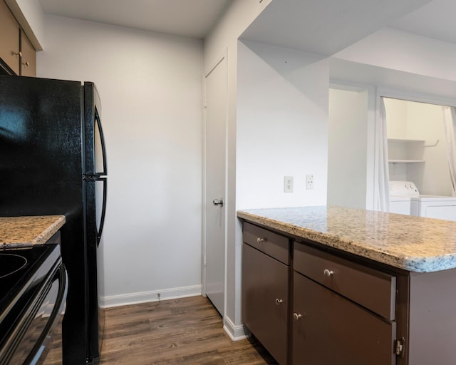 kitchen featuring dark wood-style floors, washing machine and dryer, black appliances, dark brown cabinets, and baseboards