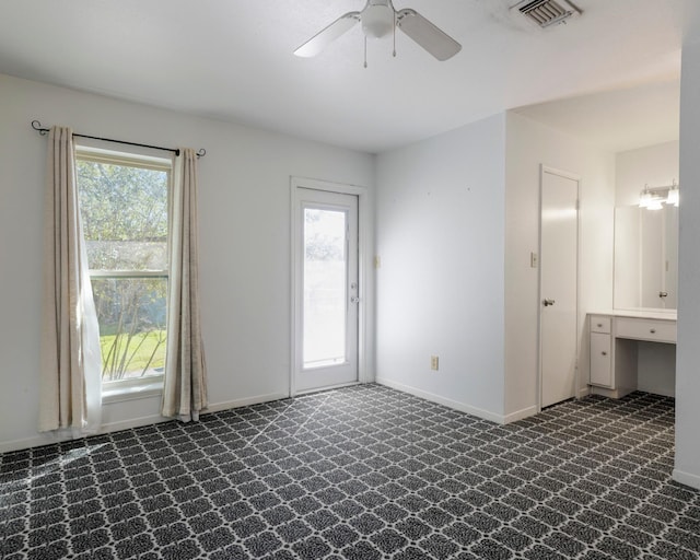 empty room featuring baseboards, visible vents, and dark colored carpet