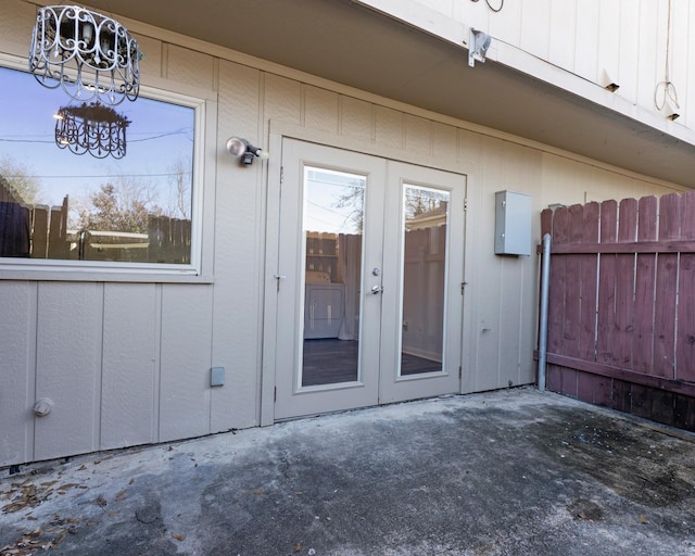 property entrance with a patio, fence, french doors, board and batten siding, and washer / dryer