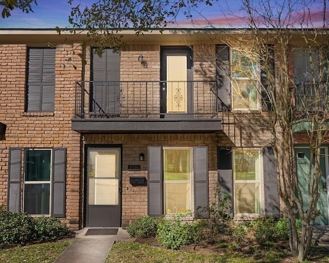 view of property featuring brick siding and a balcony