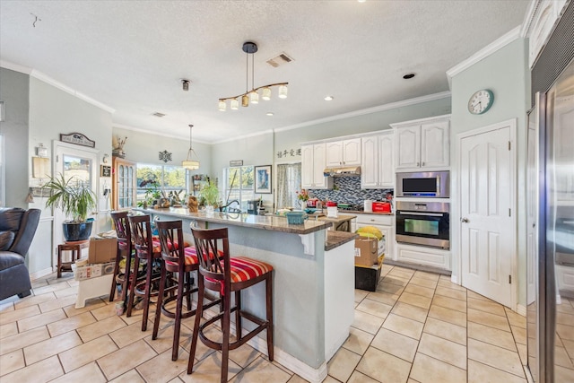 kitchen featuring light tile patterned floors, stainless steel appliances, visible vents, a kitchen breakfast bar, and backsplash