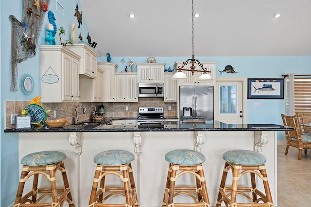 kitchen featuring a peninsula, appliances with stainless steel finishes, decorative backsplash, and a sink