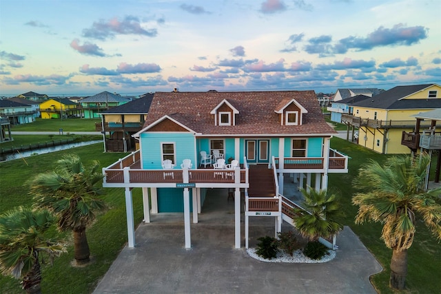 beach home featuring a shingled roof, stairs, concrete driveway, a residential view, and a carport