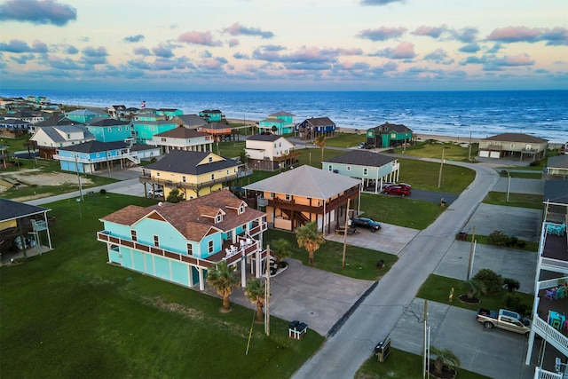 aerial view at dusk featuring a water view and a residential view