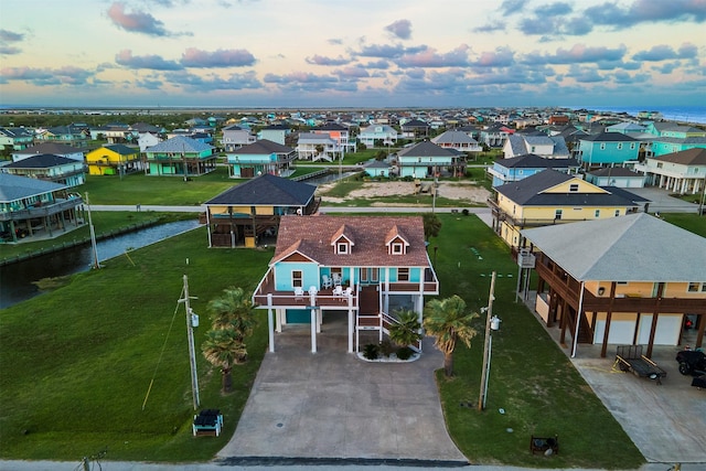 aerial view at dusk with a water view and a residential view