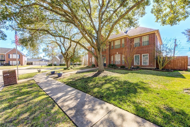 view of front of property featuring brick siding, fence, and a front lawn