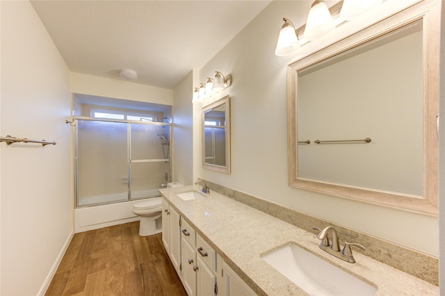 1016 Applewood Dr, Friendswood, TX 77546 - bathroom featuring toilet, double vanity, wood finished floors, enclosed tub / shower combo, and baseboards
