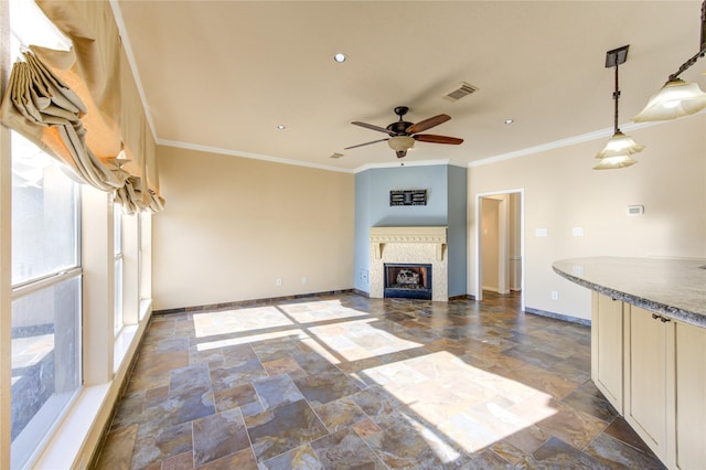unfurnished living room featuring a ceiling fan, stone tile flooring, crown molding, visible vents, and baseboards