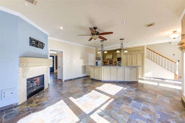 unfurnished living room with stone tile floors, visible vents, baseboards, ceiling fan, and a glass covered fireplace