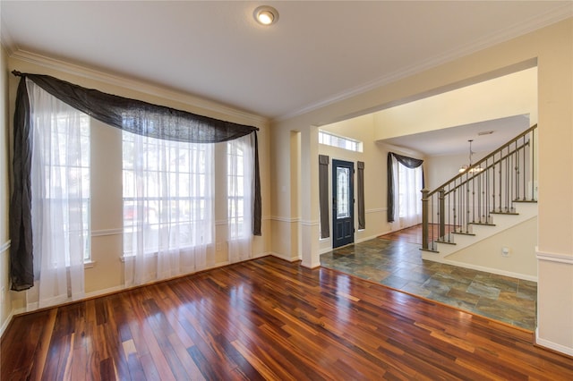 foyer entrance with baseboards, stairway, a chandelier, and crown molding