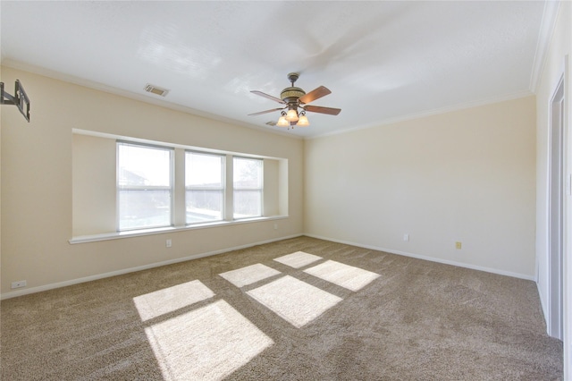 carpeted empty room featuring visible vents, baseboards, a ceiling fan, and ornamental molding