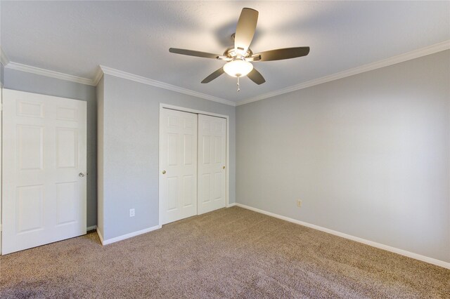 unfurnished bedroom with a closet, carpet floors, crown molding, baseboards, and ceiling fan