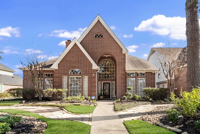 view of front of home featuring brick siding, a chimney, and a shingled roof