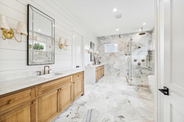 full bath featuring wooden walls, two vanities, a sink, marble finish floor, and a marble finish shower