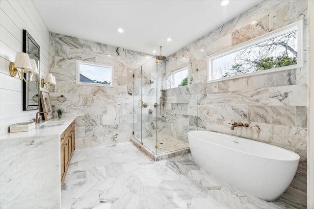 full bathroom featuring tile walls, a freestanding tub, vanity, and a marble finish shower