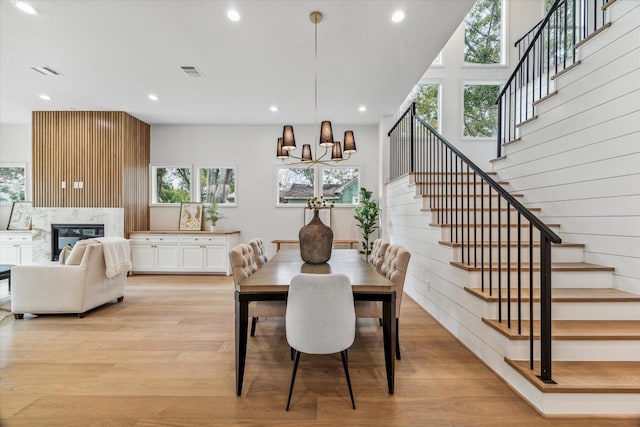 dining area featuring light wood finished floors, a fireplace, visible vents, and a wealth of natural light