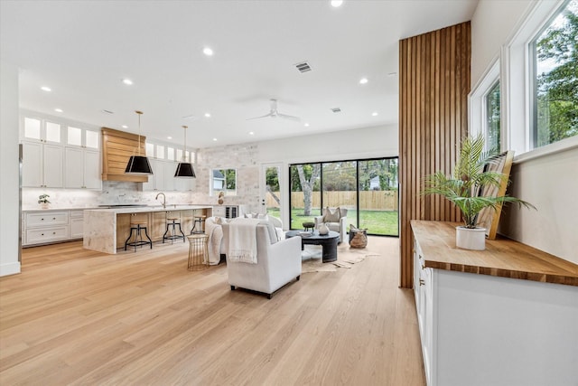 living room with light wood-style flooring, visible vents, ceiling fan, and recessed lighting