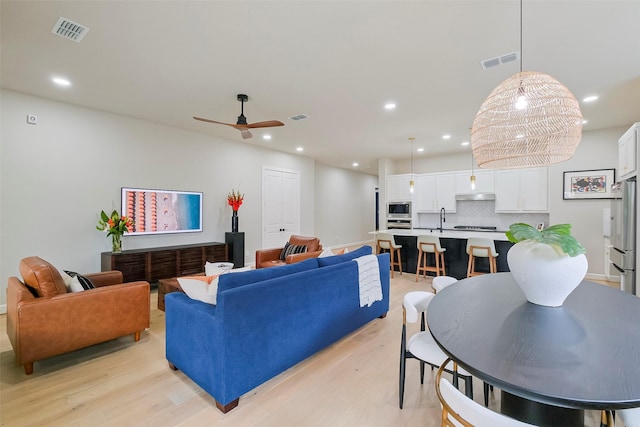 living area featuring light wood-type flooring, visible vents, and recessed lighting