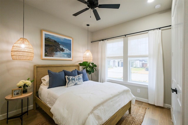 bedroom with a ceiling fan, baseboards, and wood finished floors