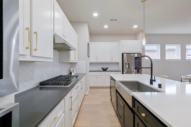 kitchen with appliances with stainless steel finishes, white cabinetry, visible vents, and under cabinet range hood