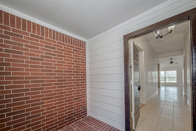 hall with wood walls, brick wall, and light tile patterned floors