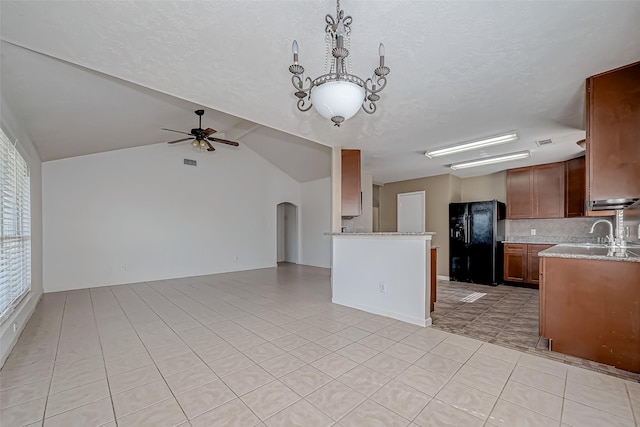 kitchen featuring arched walkways, ceiling fan, light stone counters, open floor plan, and black refrigerator with ice dispenser