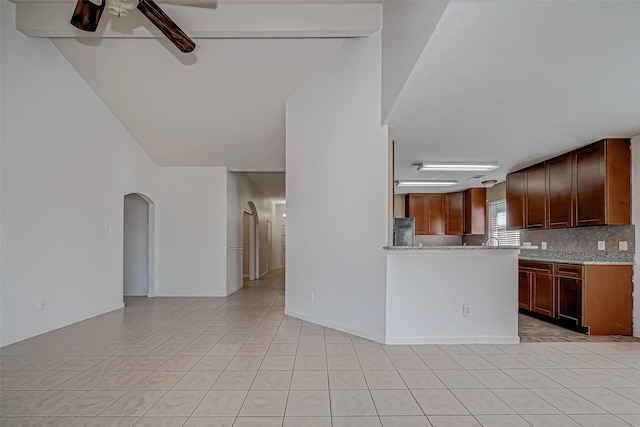 kitchen with arched walkways, tasteful backsplash, a ceiling fan, open floor plan, and light tile patterned flooring