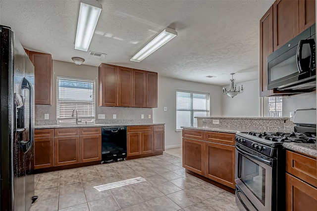 kitchen featuring light tile patterned floors, a sink, visible vents, brown cabinets, and black appliances