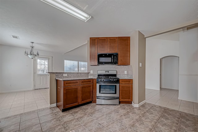 kitchen featuring visible vents, black microwave, brown cabinets, and stainless steel range with gas stovetop