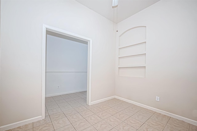 unfurnished room with built in shelves, ceiling fan, and baseboards