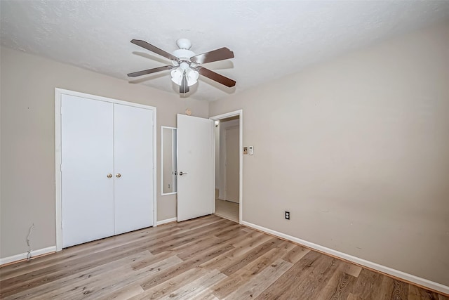 unfurnished bedroom with light wood-style floors, a closet, baseboards, and a ceiling fan