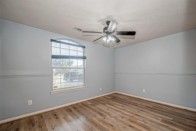 spare room featuring visible vents, ceiling fan, baseboards, and wood finished floors