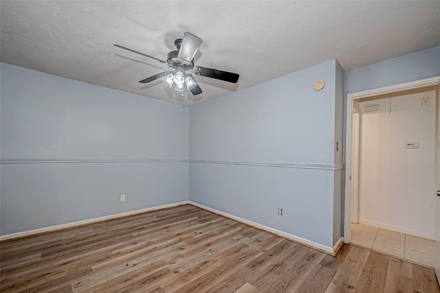 empty room featuring a ceiling fan, a textured ceiling, baseboards, and wood finished floors