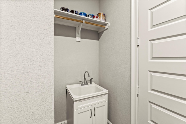 washroom featuring a sink and a textured wall