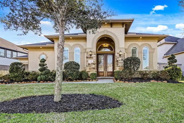 view of exterior entry with french doors, a lawn, and stucco siding