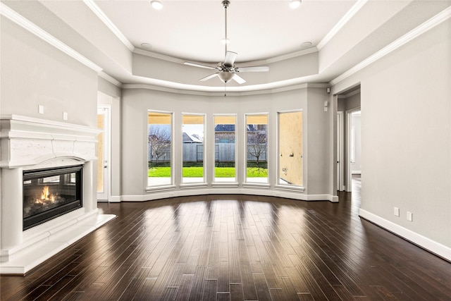 unfurnished living room featuring crown molding, a tray ceiling, a fireplace, and wood finished floors