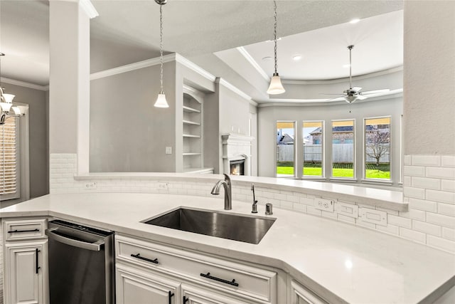 kitchen with crown molding, hanging light fixtures, a glass covered fireplace, a sink, and ceiling fan